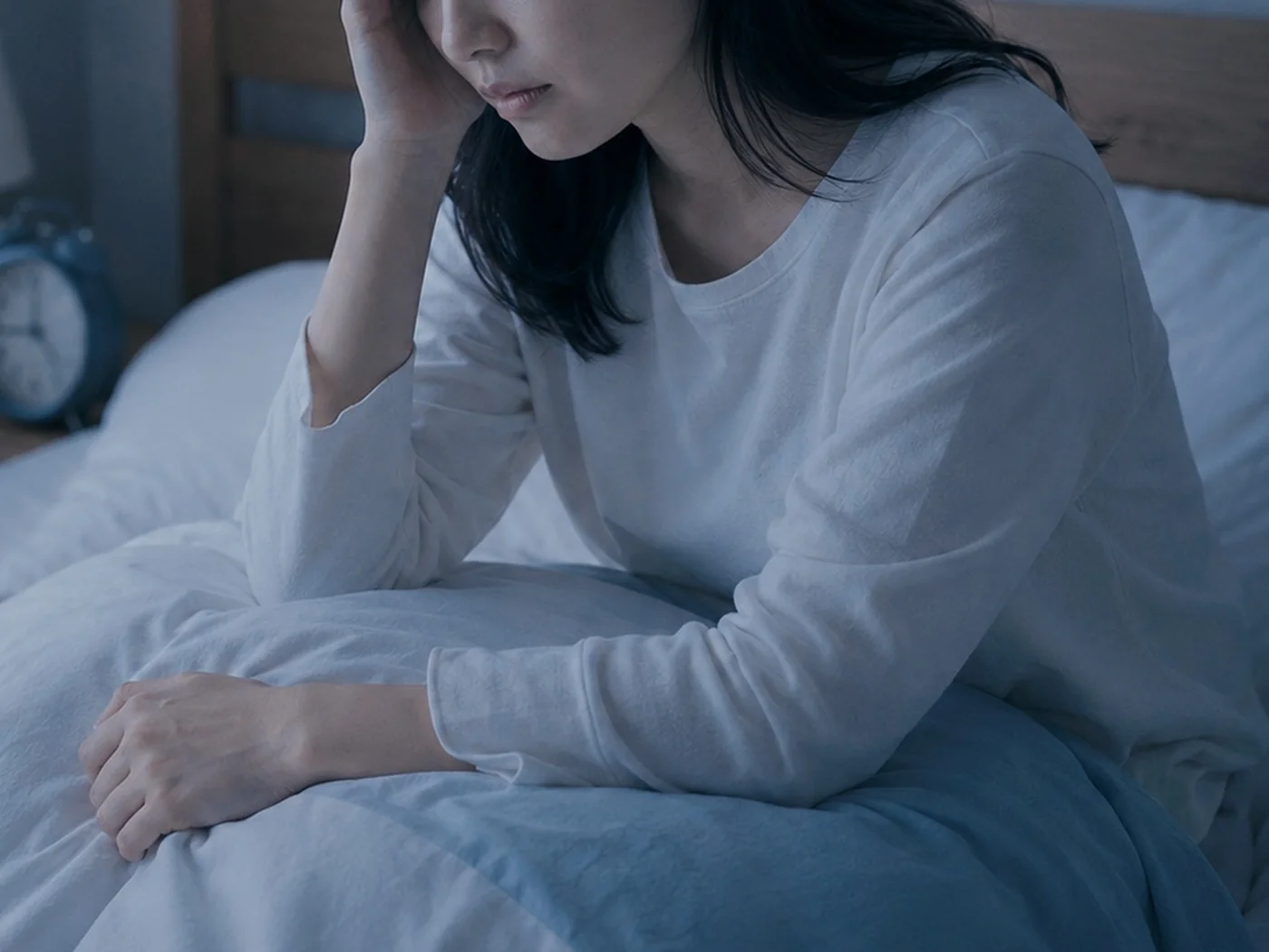 ベッドに座り、睡眠の悩みを抱える女性